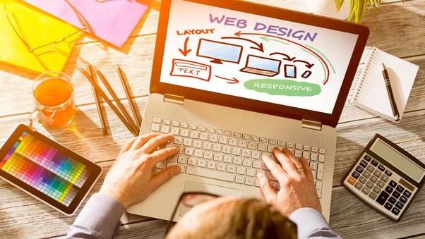 A professional web designer working on a laptop, creating a visually appealing website.